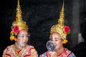 Traditional Thai dancers wearing protective face shields relax after a performance at the Erawan Shrine, which was reopened after the Thai government relaxed measures to combat the spread of the COVID-19 novel coronavirus, in Bangkok on May 4, 2020. - Thailand began easing restrictions related to the COVID-19 novel coronavirus on May 3 by allowing various businesses to reopen, but warned that the stricter measures would be re-imposed should cases increase again. (Photo by Mladen ANTONOV / AFP)
